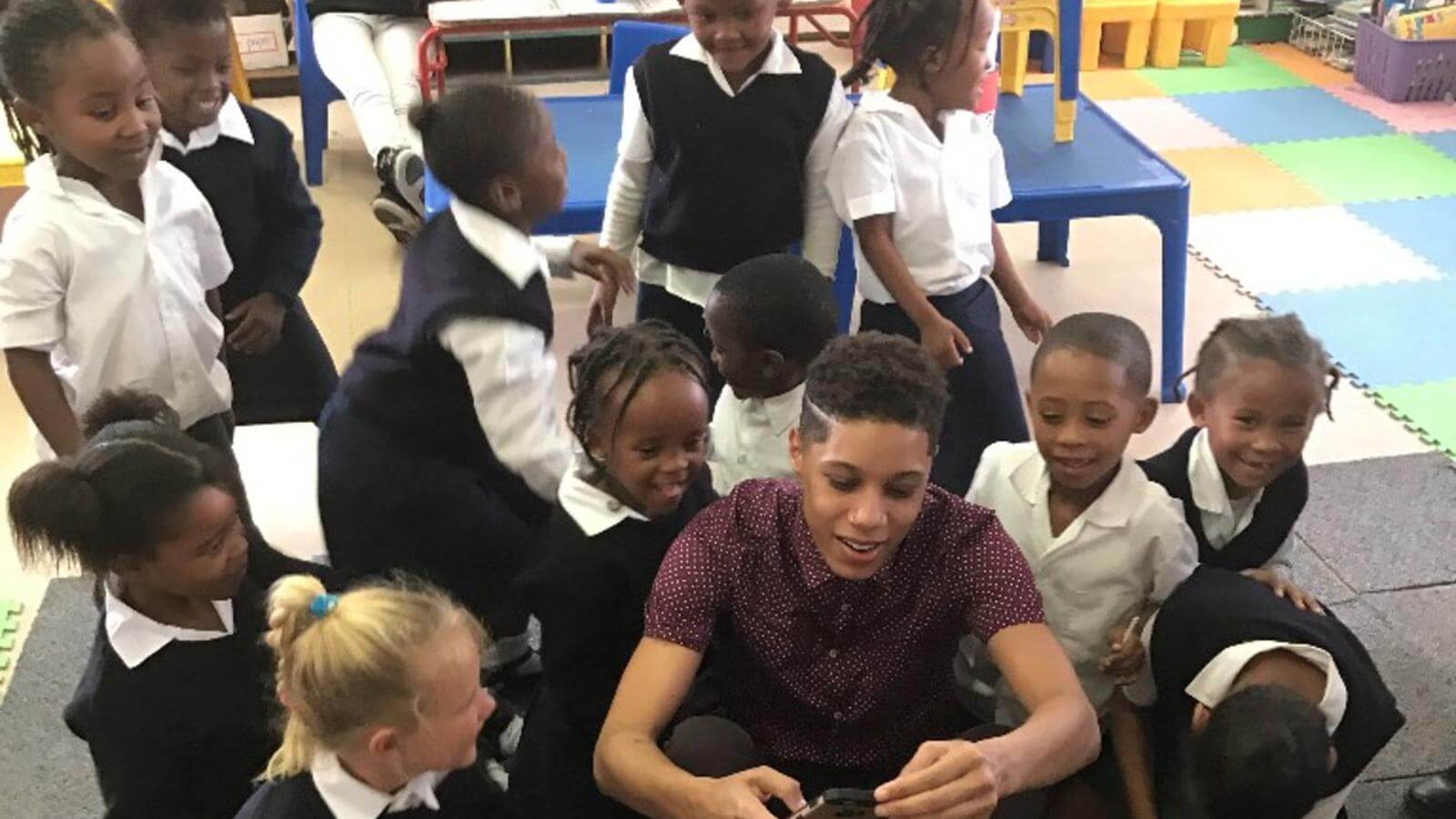 happy student surrounded by happy children taking a picture