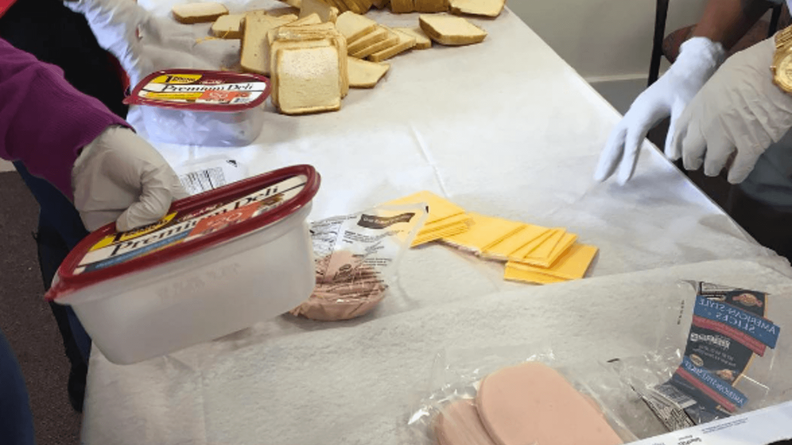Image of a person's hands serving up lunch to people