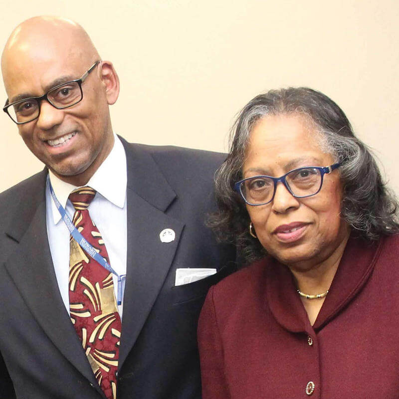 Dr. Robert Cosby and Dr. Ruby Gourdine stand together against a white wall