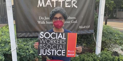 Dean Crewe poses in front of a Black Lives Matter sign with a Social Work for Social Justice poster at the Lucy Diggs Slowe street dedication.